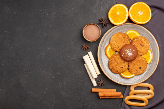 Vista superior deliciosas galletas con naranjas en rodajas sobre fondo oscuro galleta de azúcar postre galleta dulce