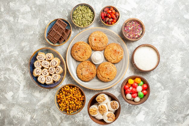 Vista superior deliciosas galletas con panecillos dulces sobre fondo blanco claro