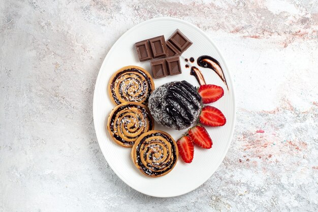 Vista superior deliciosas galletas con pastel de chocolate y fresas en el espacio en blanco