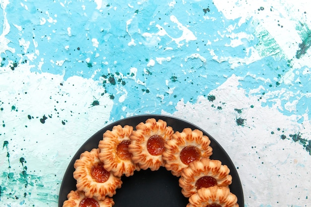 Foto gratuita vista superior de deliciosas galletas redondas formadas con mermelada dentro de la placa negra sobre fondo azul claro pastel de galleta dulce galleta