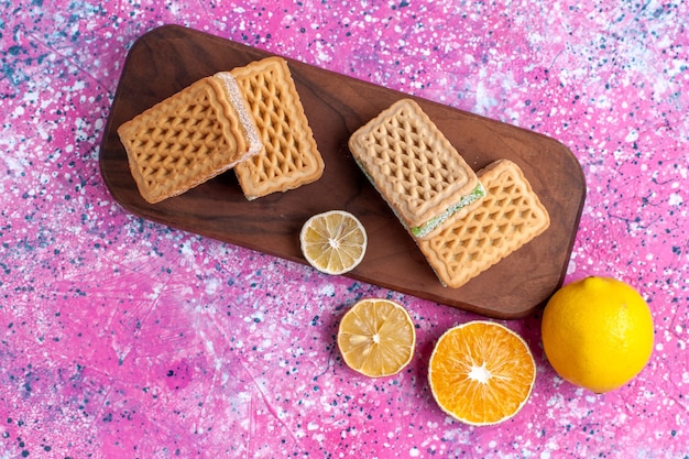 Vista superior de deliciosas galletas de sándwich con limón en el escritorio rosa.