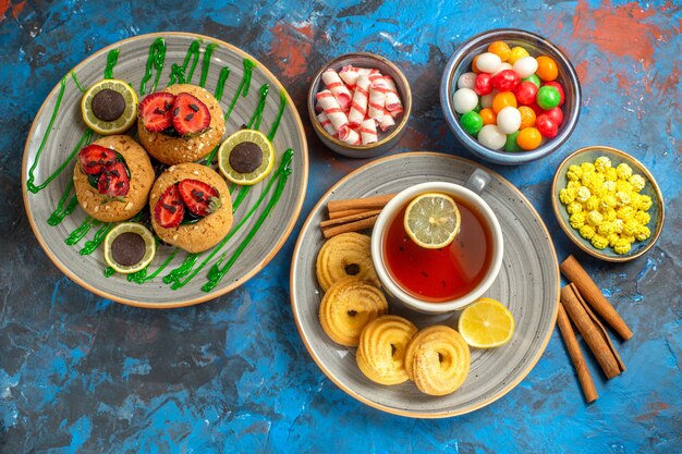 Vista superior deliciosas galletas con taza de té y caramelos en la fruta dulce de la galleta azul