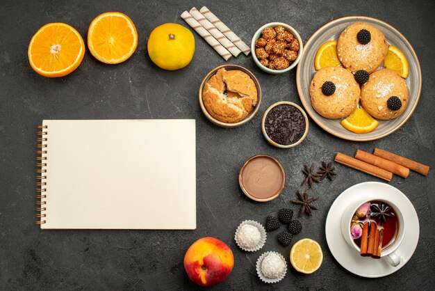 Vista superior deliciosas galletas con una taza de té en el pastel de galletas de galletas de té de escritorio oscuro