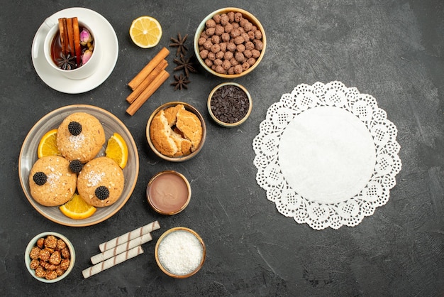 Vista superior deliciosas galletas con una taza de té en la superficie oscura pastel pastel postre azúcar galleta galletas de té