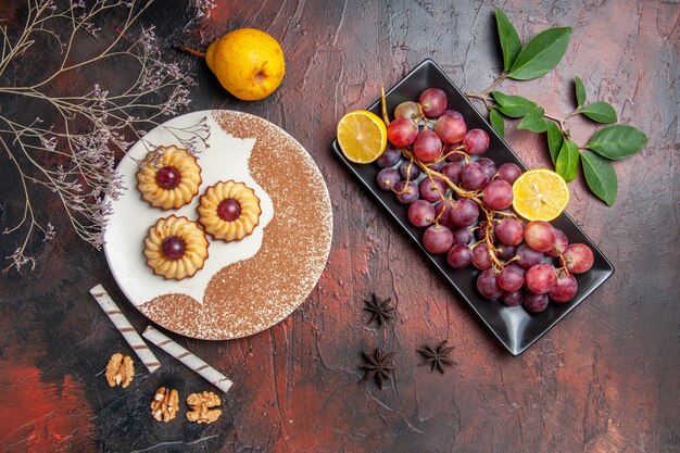 Vista superior deliciosas galletas con uvas en la mesa oscura pastel dulce galleta azúcar