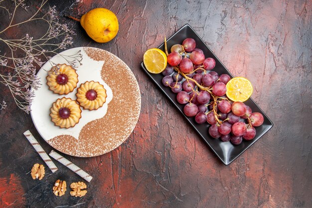 Vista superior deliciosas galletas con uvas en la mesa oscura pastel dulce galleta azúcar