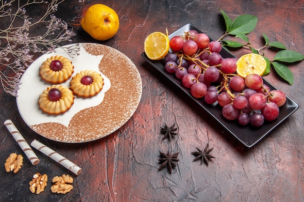 Vista superior deliciosas galletas con uvas en la mesa oscura pastel dulce galleta azúcar