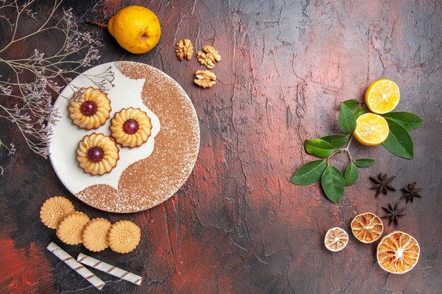 Vista superior deliciosas galletitas con frutas en mesa oscura pastel dulce galleta azúcar