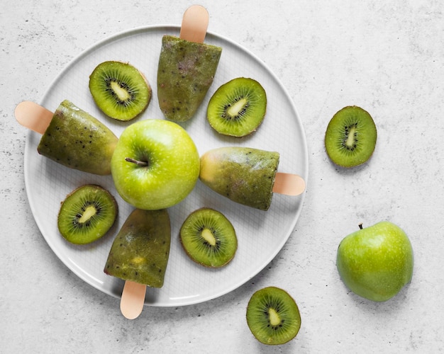 Vista superior de deliciosas paletas heladas con manzanas y kiwi