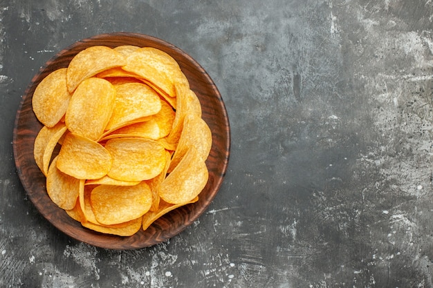 Vista superior de deliciosas papas fritas caseras en una placa marrón sobre fondo gris