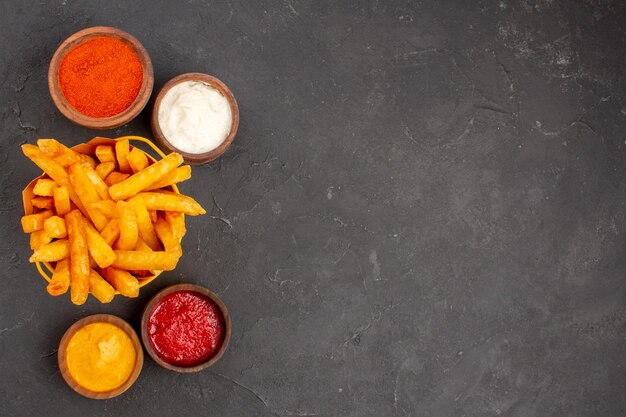 Vista superior deliciosas papas fritas con salsas en el fondo oscuro plato hamburguesa comida rápida papa comida