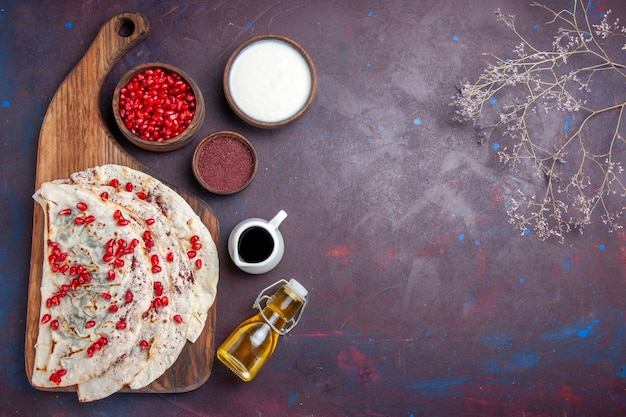 Vista superior de deliciosas pitas de carne qutabs con granadas rojas frescas sobre un piso oscuro comida comida de masa pita