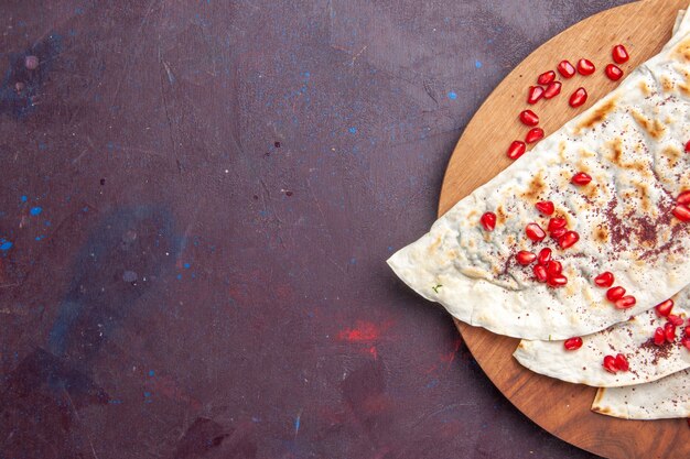 Vista superior de deliciosas pitas de qutabs de carne con granadas rojas frescas en el escritorio púrpura masa de carne pita comida