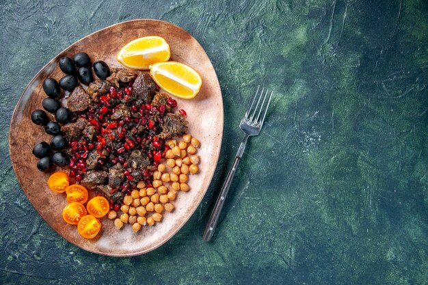 Vista superior deliciosas rebanadas de carne frita con frijoles uvas y rodajas de limón dentro de la placa