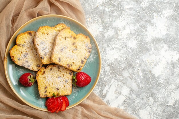 Vista superior de deliciosas rebanadas de pastel con fresas frescas a la luz