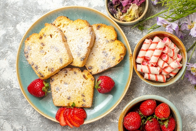 Vista superior de deliciosas rebanadas de pastel con fresas a la luz