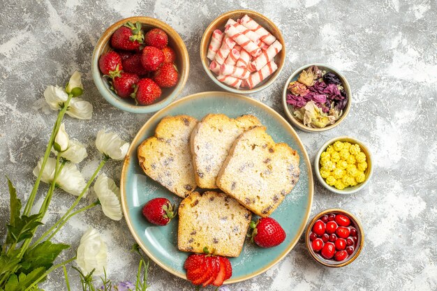 Vista superior de deliciosas rebanadas de pastel con fresas a la luz