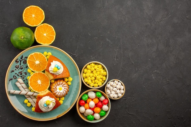 Vista superior de deliciosas rebanadas de pastel con galletas de tubo y mandarinas frescas sobre fondo oscuro pastel de frutas pastel de galletas dulces