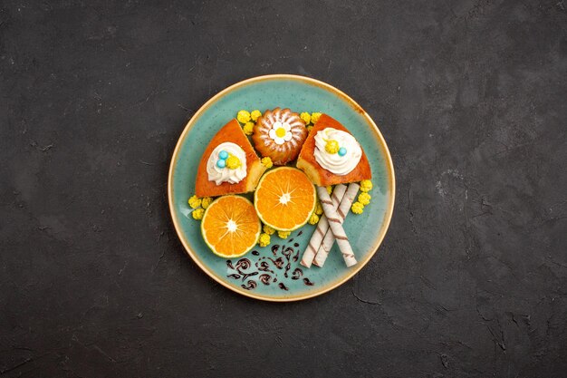 Vista superior de deliciosas rebanadas de pastel con galletas de tubo y rodajas de mandarinas sobre un fondo oscuro pastel de frutas cítricas pastel de galletas té dulce