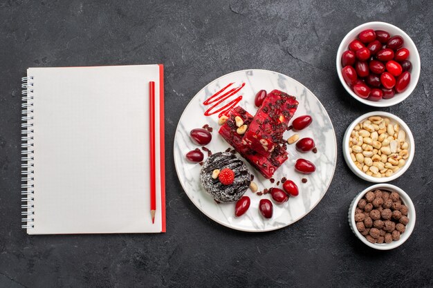 Vista superior de deliciosas rebanadas de pastel con nueces y cornejos en el escritorio gris