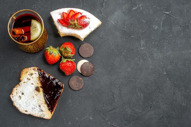 Vista superior de deliciosas rebanadas de pastel con taza de té en una superficie oscura