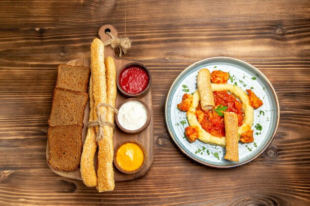 Vista superior deliciosas rebanadas de pollo con pan de papas trituradas y condimentos en el escritorio de madera comida de papa picante pimiento