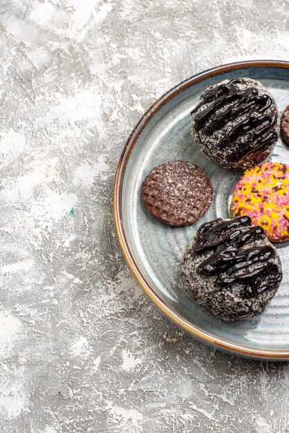 Vista superior de deliciosas tortas de bolas de chocolate con galletas en superficie blanca