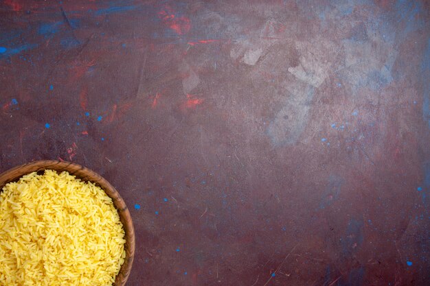 Vista superior del delicioso arroz cocido dentro de la placa marrón en el escritorio oscuro