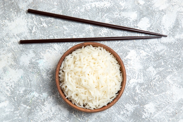 Foto gratuita vista superior del delicioso arroz cocido dentro de la placa marrón sobre blanco