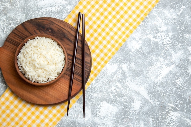 Foto gratuita vista superior del delicioso arroz cocido dentro de la placa marrón sobre blanco