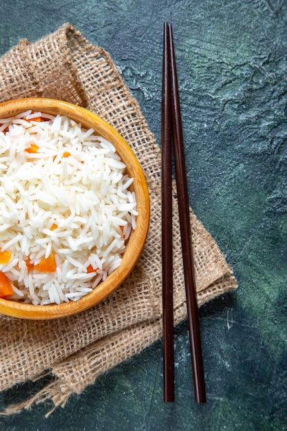 Vista superior del delicioso arroz hervido dentro del plato pequeño en el escritorio oscuro