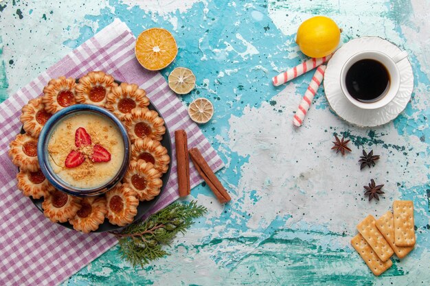 Vista superior del delicioso azúcar con taza de café y postre de fresa en superficie azul