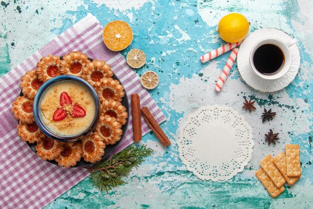 Vista superior del delicioso azúcar con taza de café y postre de fresa en superficie azul