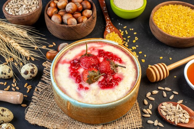 Vista superior del delicioso desayuno servido con mermelada de fresas en un tazón y huevos de avellanas arroz amarillo sobre fondo de color oscuro