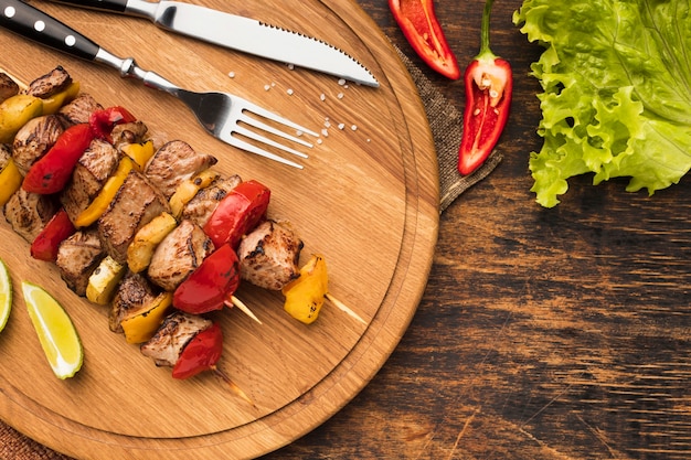 Vista superior del delicioso kebab en tabla de cortar con ensalada y cubiertos