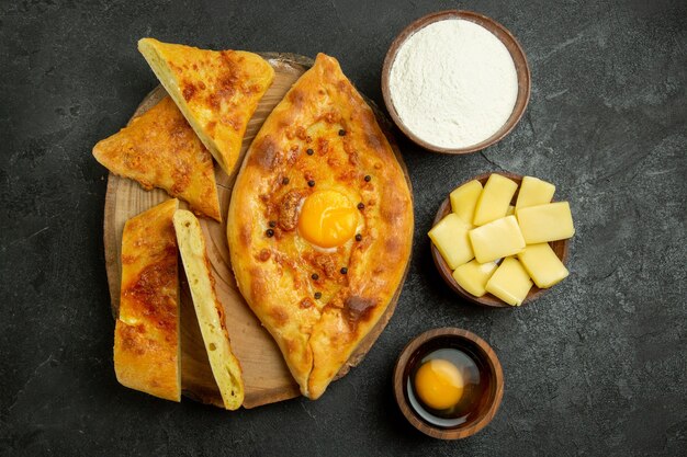 Vista superior del delicioso pan de huevo al horno en rodajas con queso y harina en el espacio gris