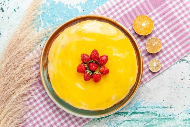 Vista superior delicioso pastel con almíbar amarillo y fresas rojas frescas en la superficie azul claro pastel de galletas hornear té de pastel de azúcar dulce