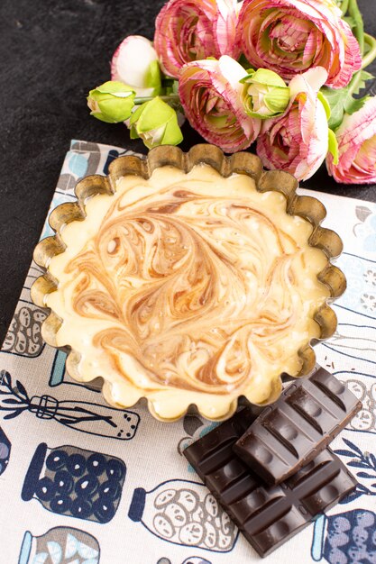 Una vista superior delicioso pastel de café chocolate dulce delicioso pastel de panadería de azúcar dulce junto con rosas en el oscuro escritorio