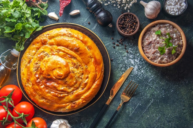 Vista superior del delicioso pastel de carne con ingredientes en superficie oscura