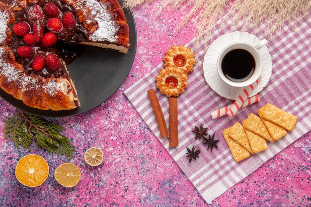 Vista superior delicioso pastel de chocolate con galletas galletas y taza de té en el escritorio rosa pastel de galletas dulces de azúcar