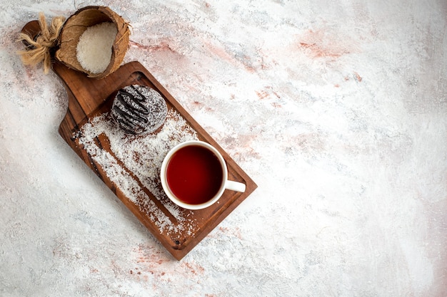 Vista superior delicioso pastel de chocolate con taza de té sobre fondo blanco pastel de chocolate galleta azúcar dulce té galleta