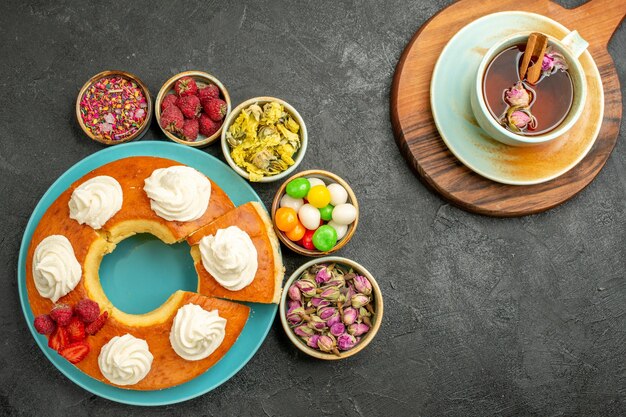 Vista superior del delicioso pastel de crema con una taza de té en la oscuridad