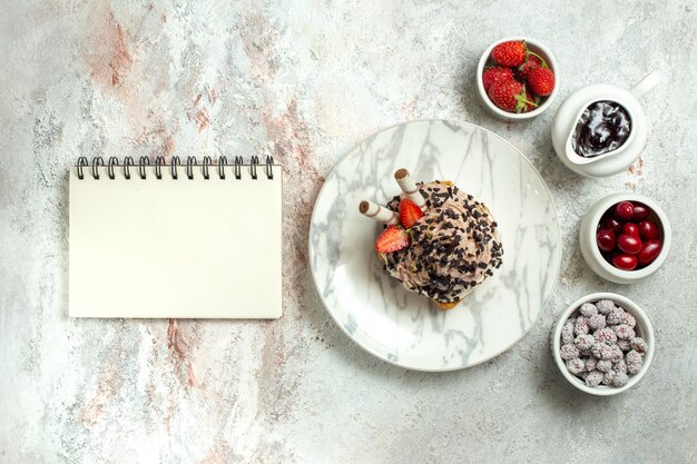 Vista superior delicioso pastel cremoso con fresas y dulces en la superficie blanca pastel de té de cumpleaños galleta crema dulce