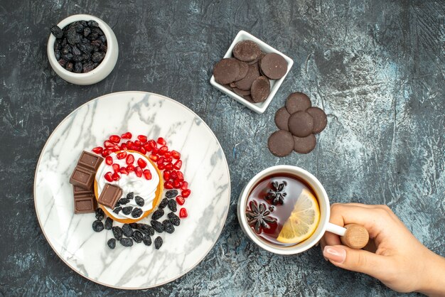 Vista superior delicioso pastel cremoso con galletas choco y taza de té en el fondo claro-oscuro