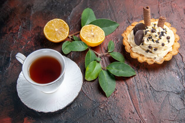 Vista superior delicioso pastel cremoso con taza de té en el postre dulce pastel de mesa oscura