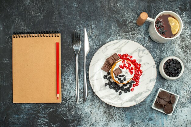 Vista superior delicioso pastel cremoso con taza de té sobre fondo claro-oscuro