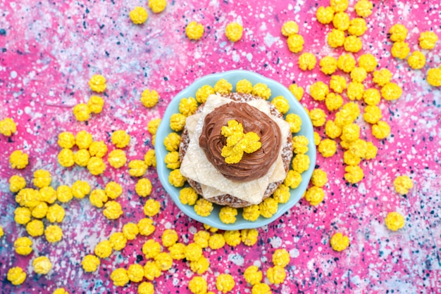 Foto gratuita vista superior del delicioso pastel dulce con crema dentro de la placa con caramelos amarillos en el fondo colorido pastel galleta masa de azúcar hornear color