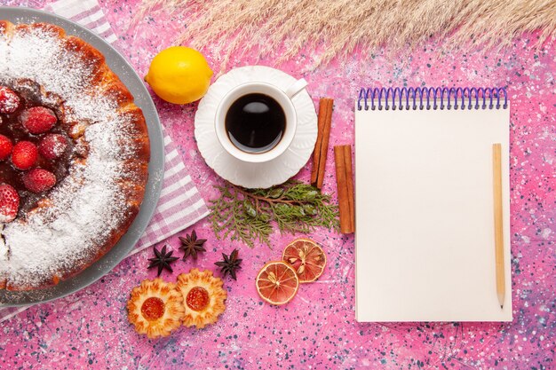 Vista superior delicioso pastel de fresa azúcar en polvo con bloc de notas de galletas y té en el fondo rosa pastel dulce azúcar galleta galleta té