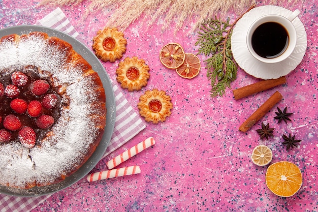 Vista superior delicioso pastel de fresa azúcar en polvo con galletas y una taza de té en el fondo rosa pastel dulce azúcar galleta galleta té