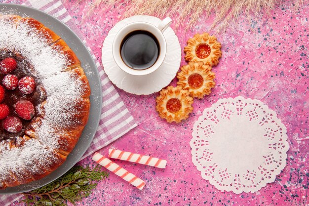 Vista superior delicioso pastel de fresa azúcar en polvo con galletas y té en el fondo de color rosa claro pastel de galletas dulces té